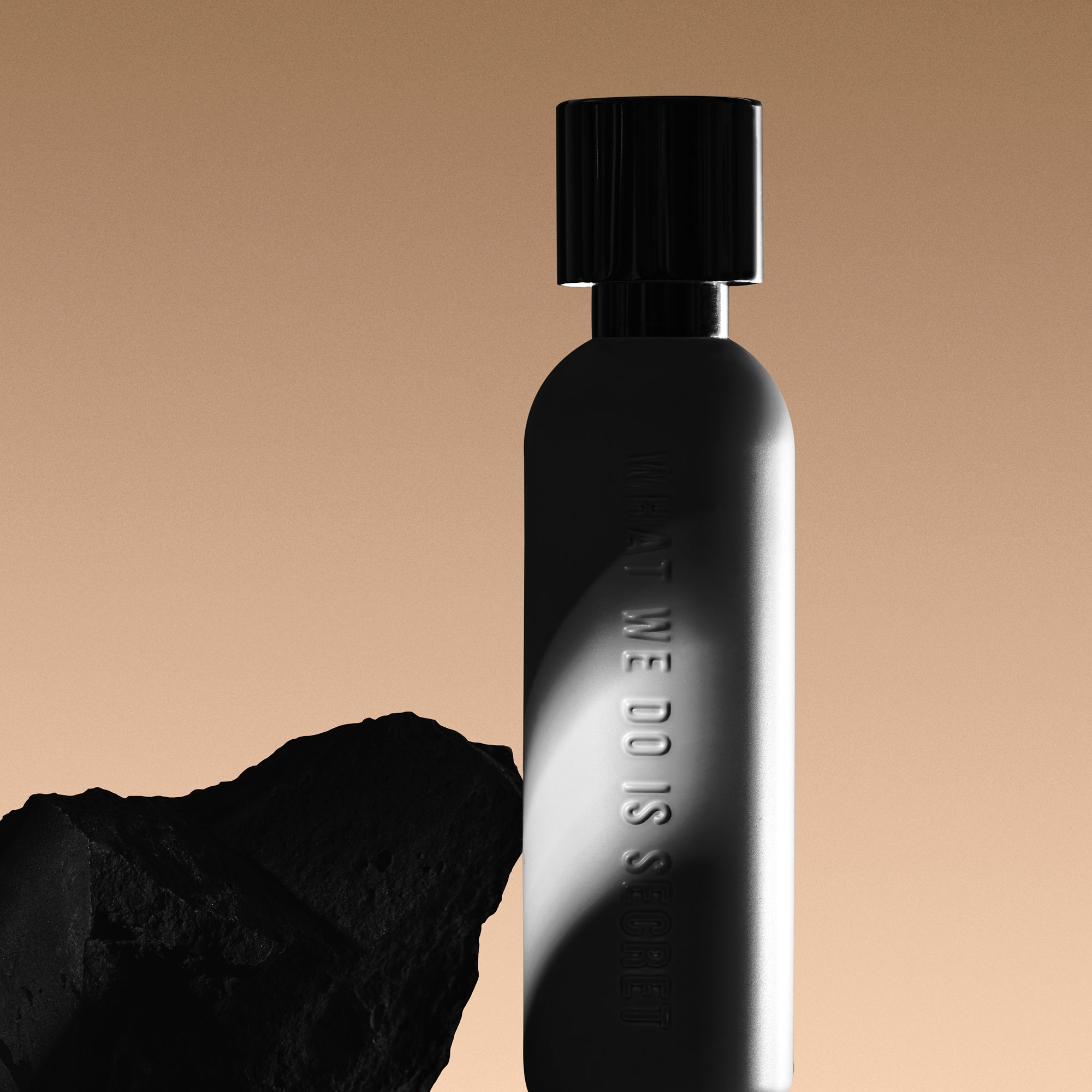 Black perfume bottle with 'WE DO' text on a beige background